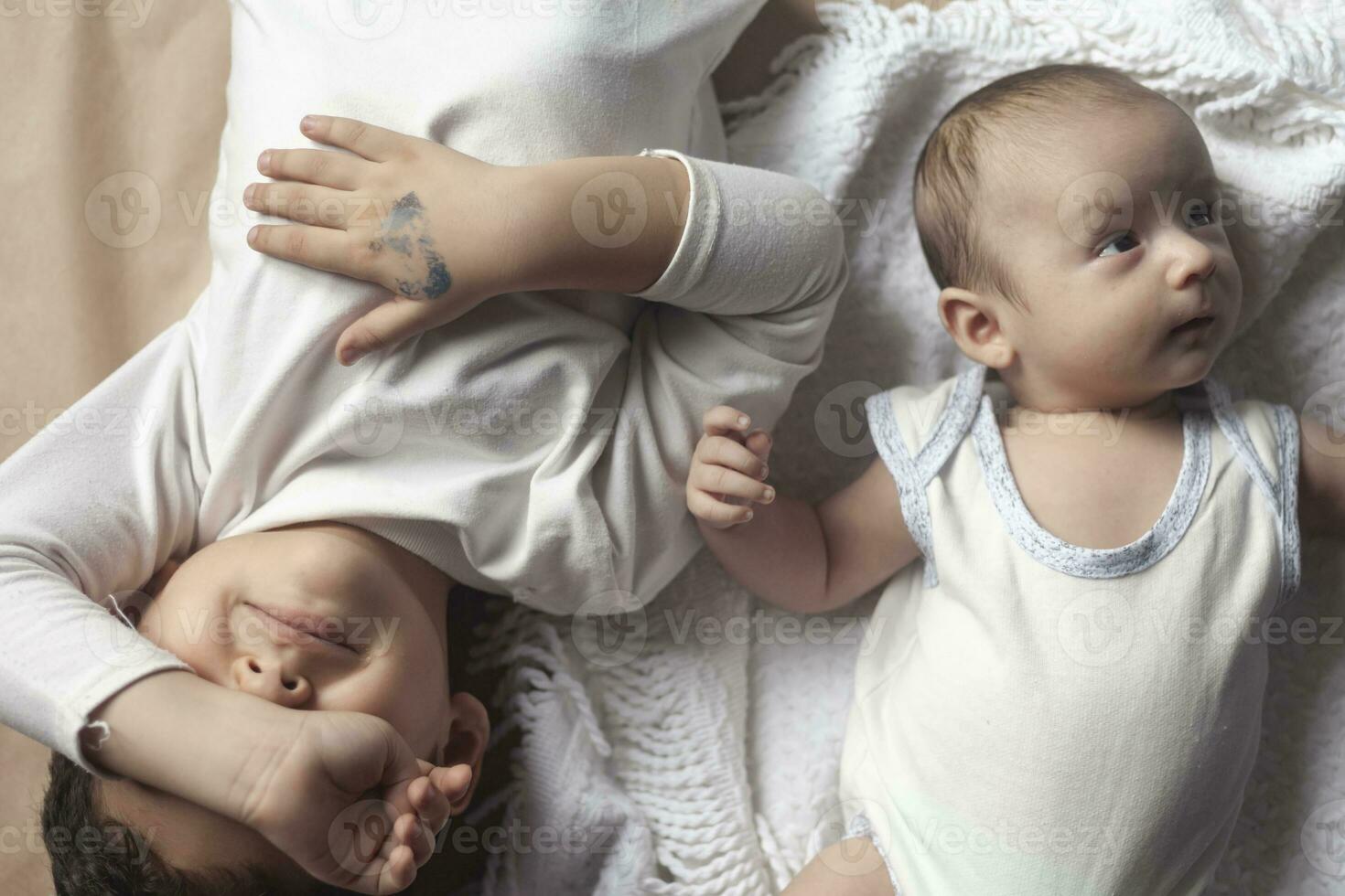 Two brothers lying and posing. Portrait of brothers. Two months baby boy and five years small boy playing cheerfully. View from above. Emotional expressions of children. photo