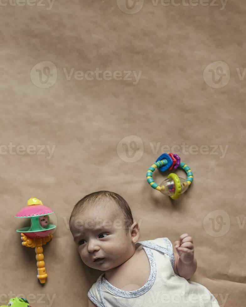 recién nacido bebé chico acostado con juguetes de cerca de adorable linda recién nacido bebé chico de dos meses y juguetes encantador niño jugando foto