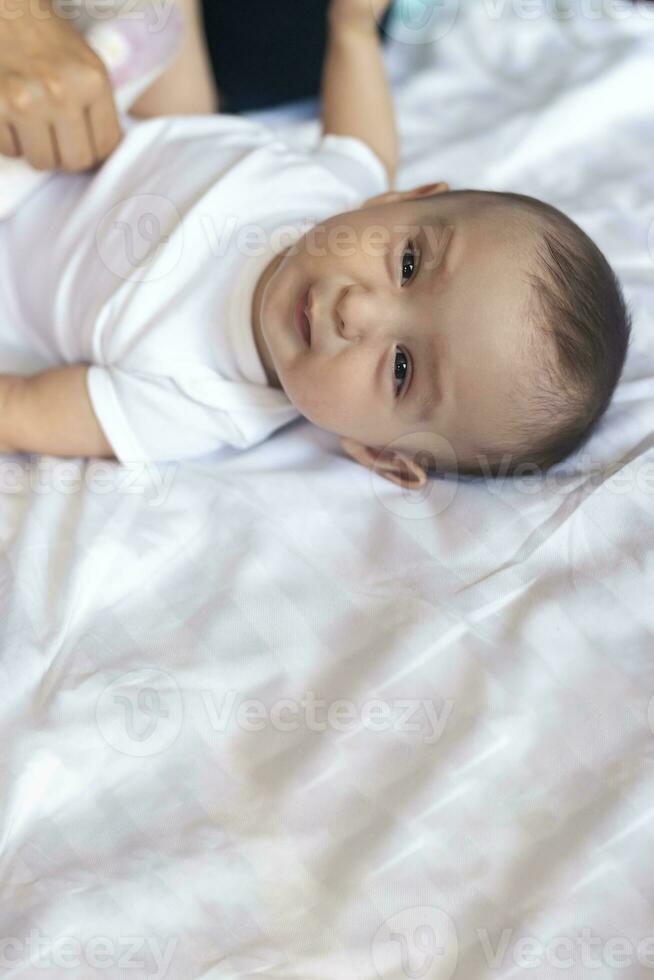 Angry 6 months old baby in bed. Little baby boy feeling uncomfortable and unhappy. Sad baby boy looking at camera. Copy space photo