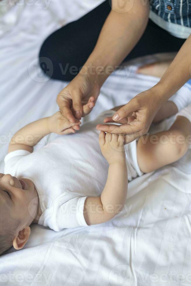 Baby massage. Mom doing gymnastics with kid. Mommy massaging cute baby boy. Moving baby's legs to help relieve constipation. Young mother doing exercises and movements to stimulate baby's bowels. photo