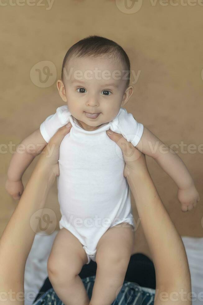 madre y bebé. mamá participación su 6 6 meses bebé chico. hermosa bebé chico de seis meses en su de la madre manos. joven medio oriental madre participación en su brazos su pequeño hijo foto