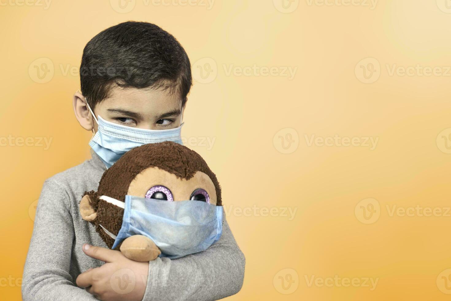 Little preschool kid playing with his toy monkey in medical face mask photo
