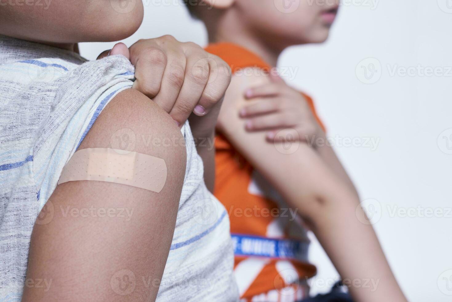 Two boys showing their arm with adhesive bandage plaster after vaccination. Injection covid vaccine, immunization for family photo