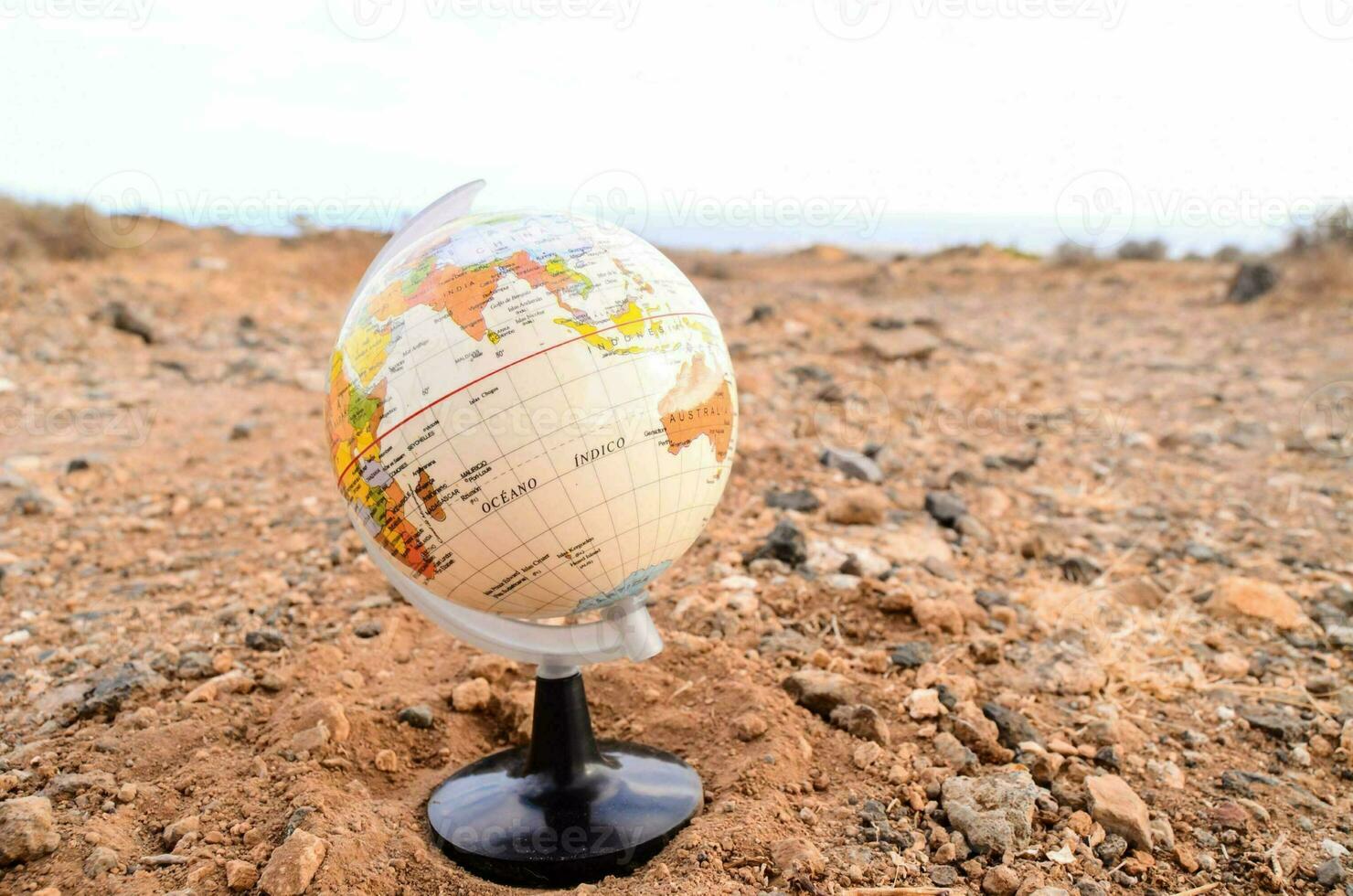 a globe on a stand in the middle of a desert photo