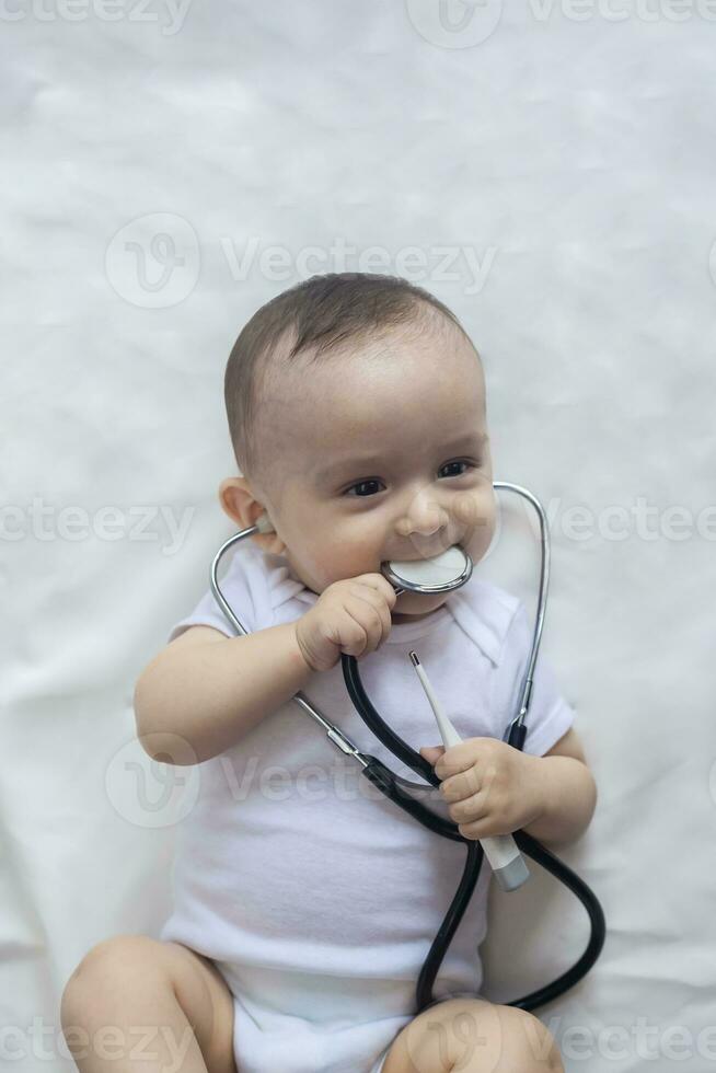 Little cute baby doctor. 6-month old baby boy playing with stethoscope. Kid having fun like a doctor photo