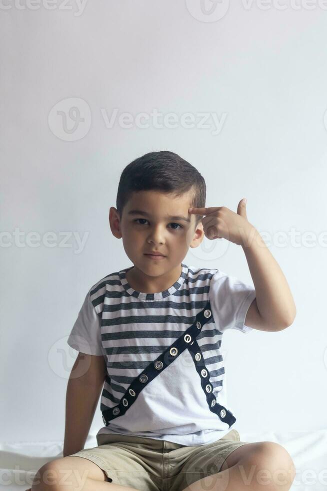 Six years boy portrait. Innocent smiling little boy on grey background. Little boy contorts his face. People, childhood lifestyle concept. photo