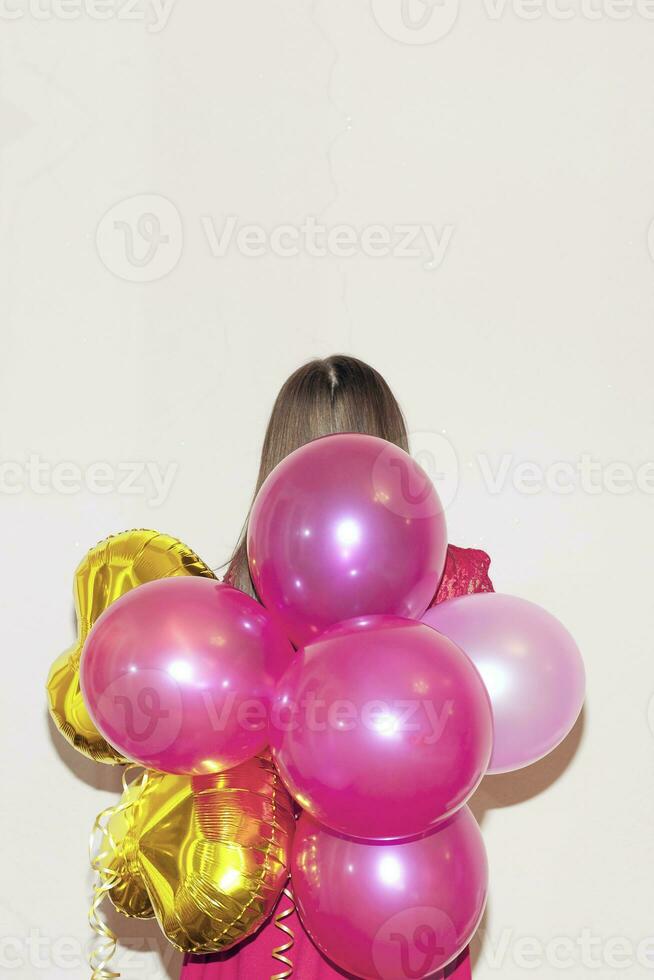 Woman stands backside holding bunch of colored air balloons. photo