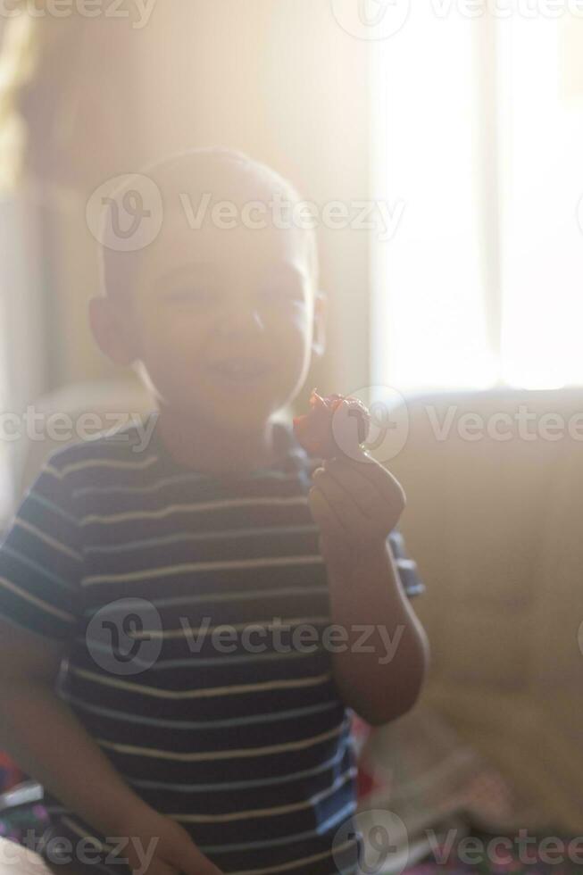 A little boy eating strawberries. Summer food. A young kid eats a yummy strawberry in hot summer day photo