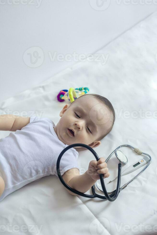 Little cute baby doctor. 6-month old baby boy playing with stethoscope. Kid having fun like a doctor photo