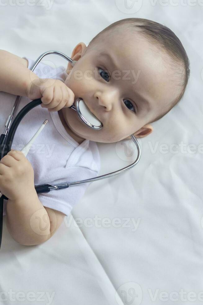 pequeño linda bebé doctor. 6 meses antiguo bebé chico jugando con estetoscopio. niño teniendo divertido me gusta un médico foto