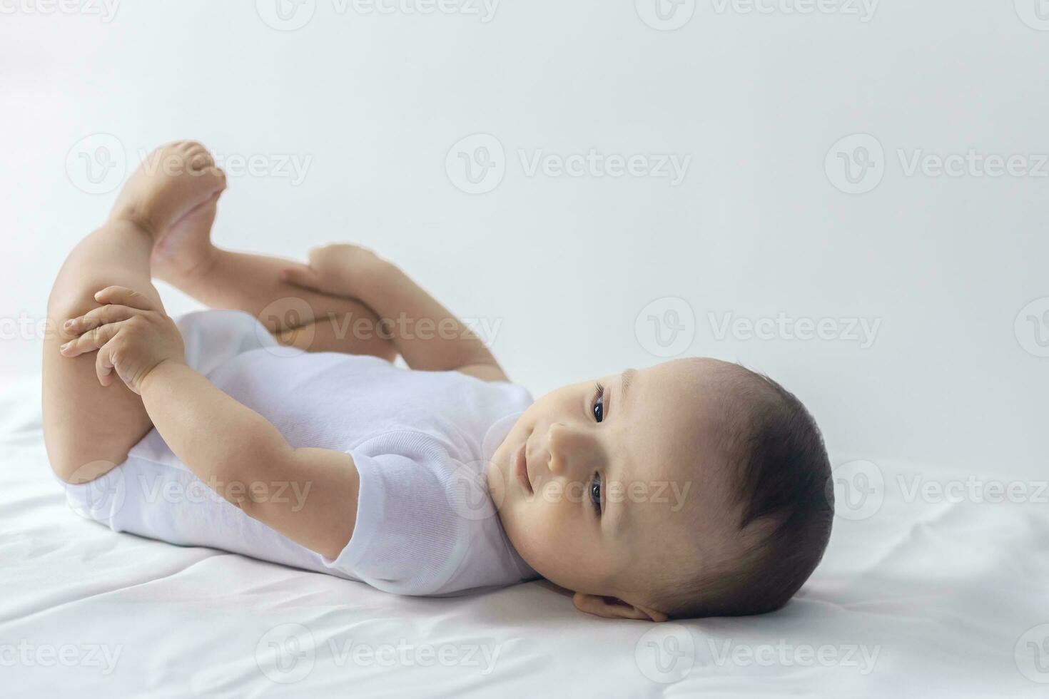 6-month baby having fun in white bedding. Cute baby lying on bed. Family, new life, childhood concept. photo