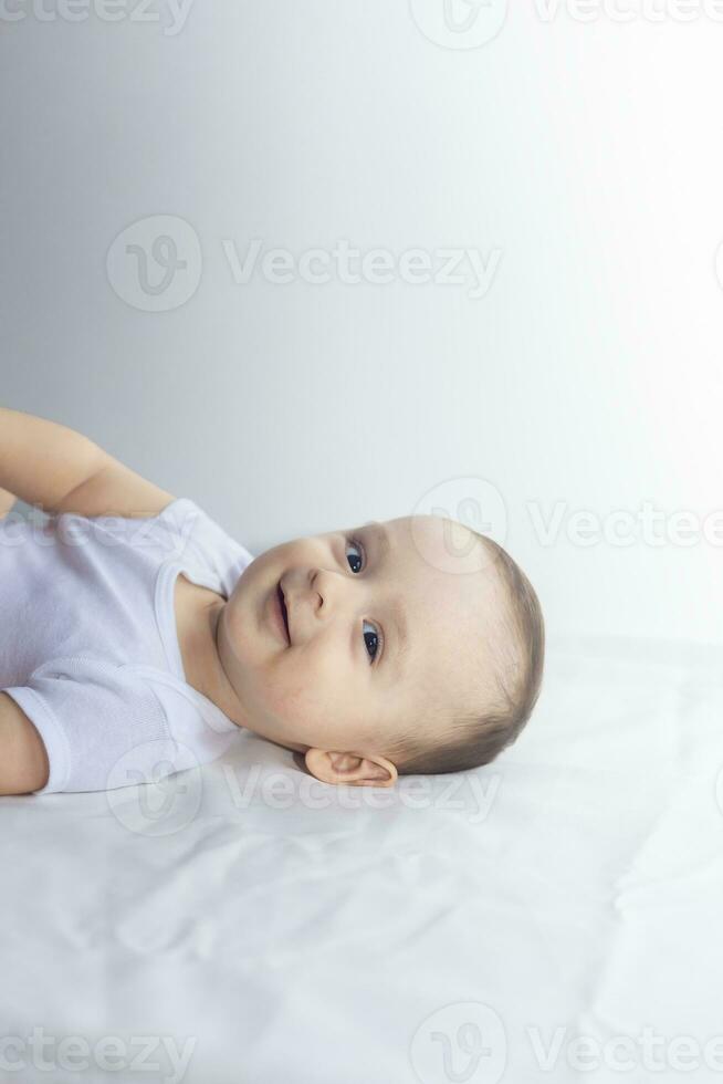 6-month baby having fun in white bedding. Cute baby lying on bed. Family, new life, childhood concept. photo