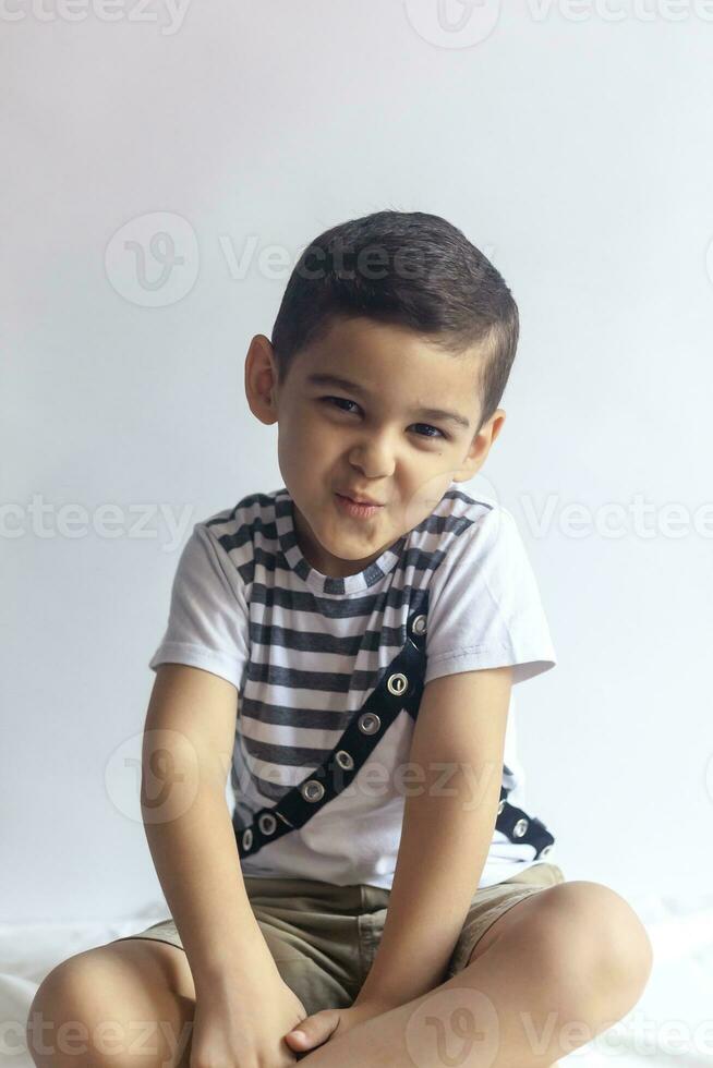 Six years boy portrait. Innocent smiling little boy on grey background. Little boy contorts his face. People, childhood lifestyle concept. photo