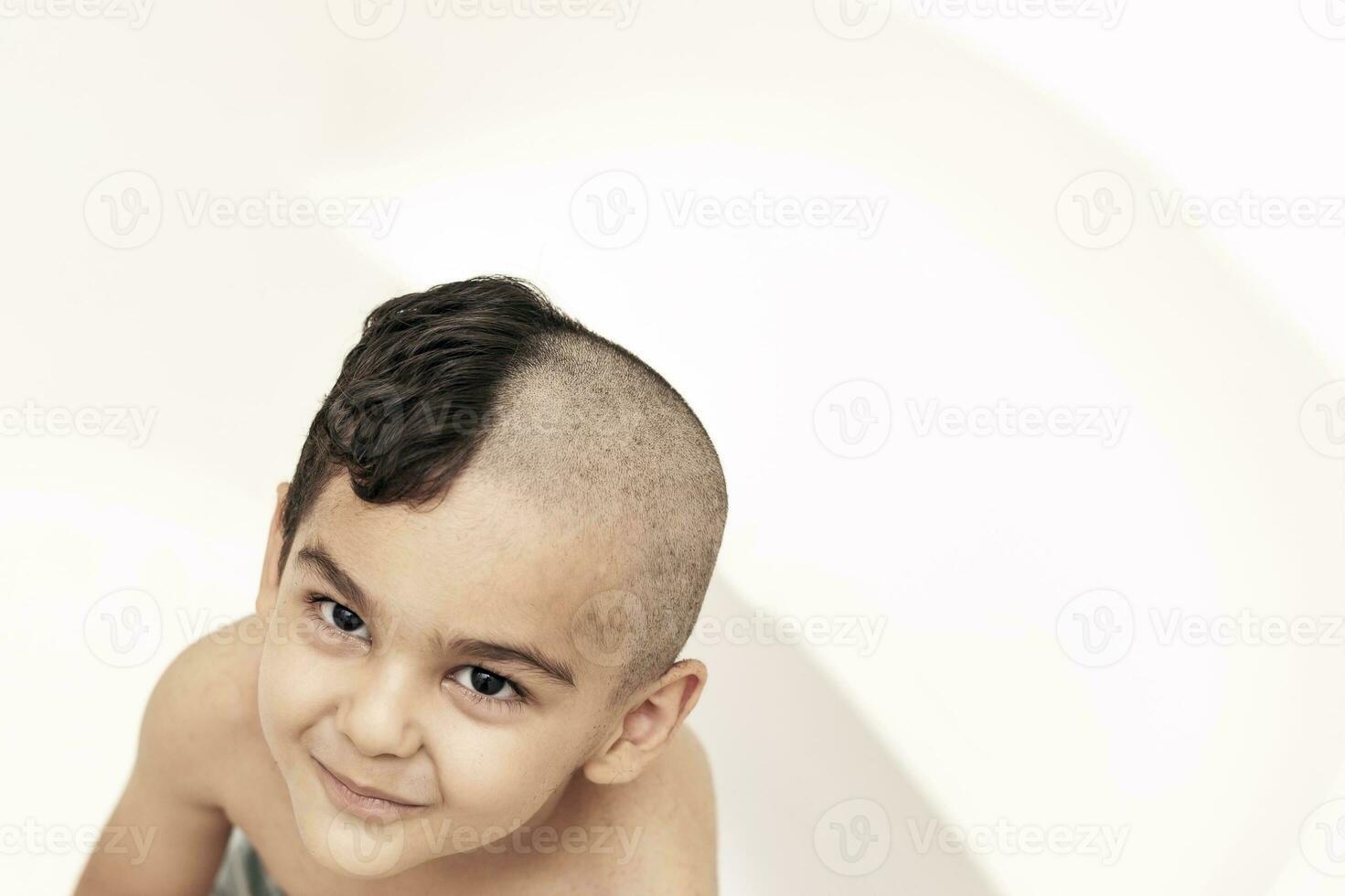 seis años chico a Corte de pelo a hogar. padre cortar medio de el hijos pelo apagado a el baño foto