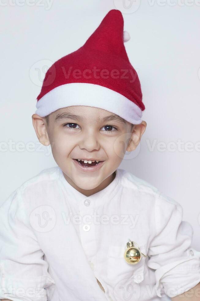 contento pequeño Navidad chico. celebrando Navidad. 6-7 año antiguo niño con Papa Noel sombrero. foto