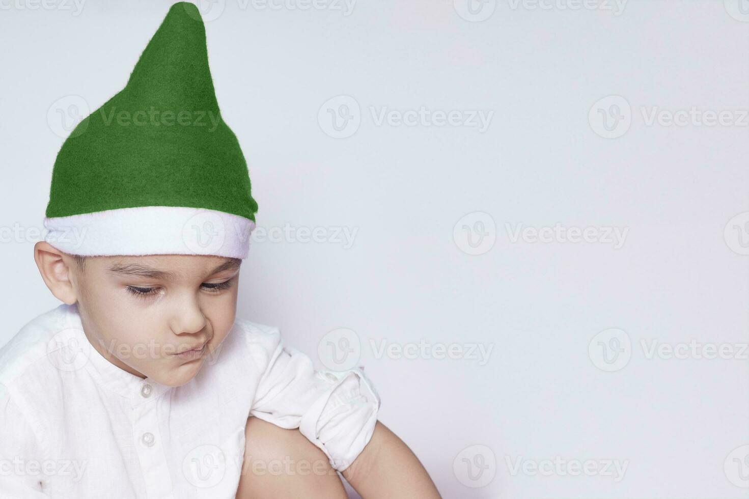 un pequeño niño haciendo un gracioso irritado rostro. irritado Navidad chico en Papa Noel sombrero. un De Verdad grave y hermoso niño foto