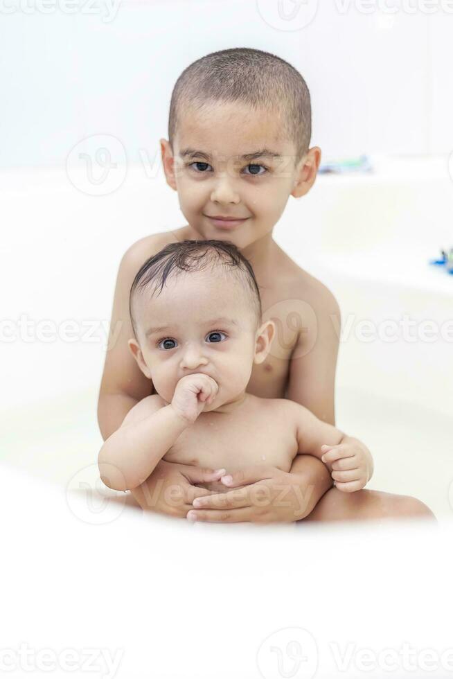 dos hermanos teniendo agua divertido en bañera foto