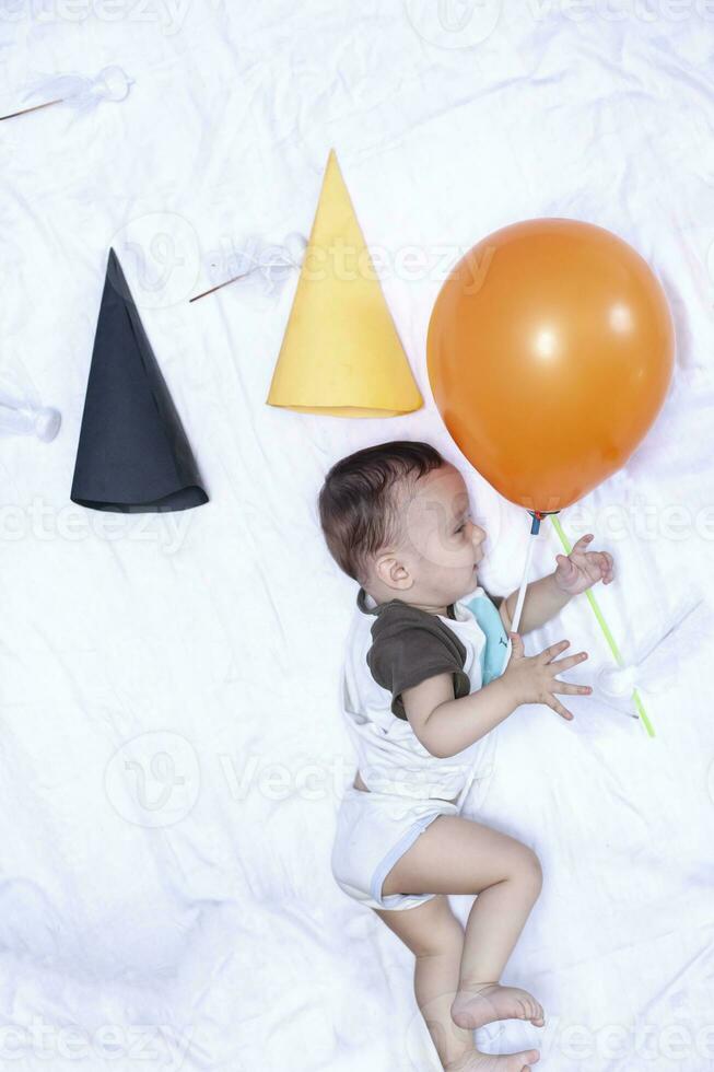 bebé jugando con un globo. primero cumpleaños. bebé chico acostado a su cama foto
