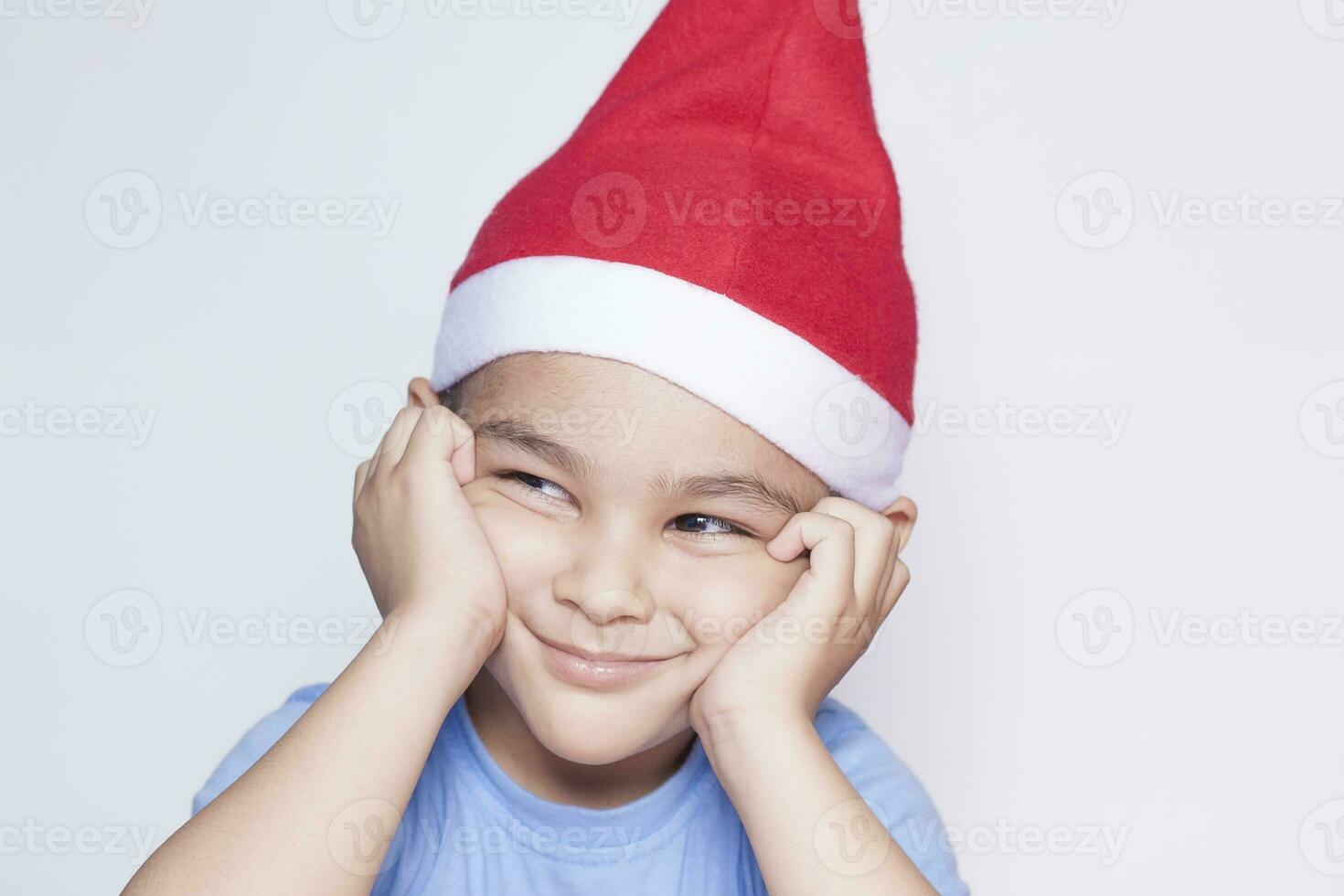 A little kid making funny annoyed face. Annoyed Christmas Boy in Santa Hat photo