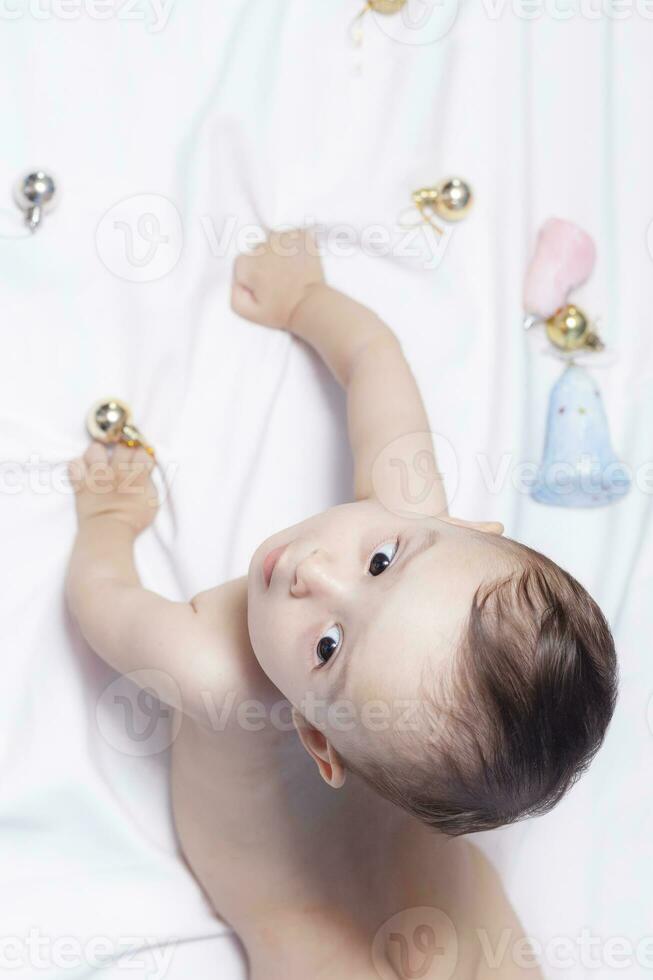 Baby boy playing with christmas balls and toys photo