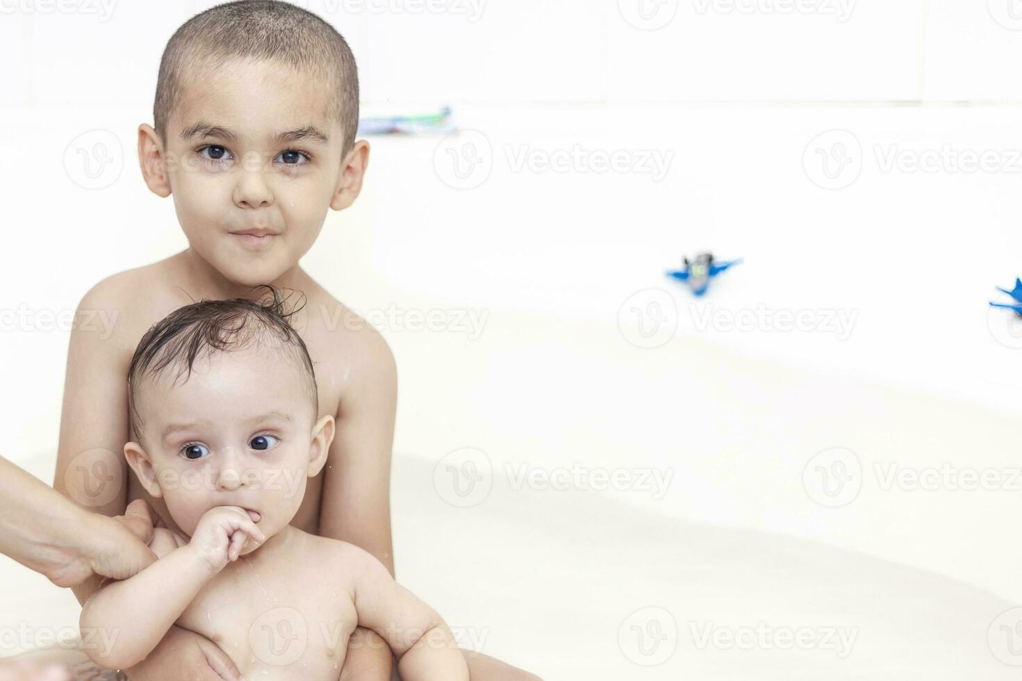 dos hermanos teniendo agua divertido en bañera foto