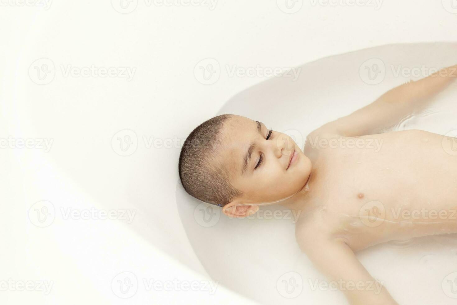 chico toma un baño. 5-6 años niño teniendo agua divertido en baño. foto