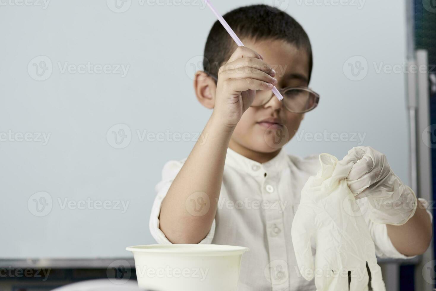 Little boy scientist in white making experiments photo