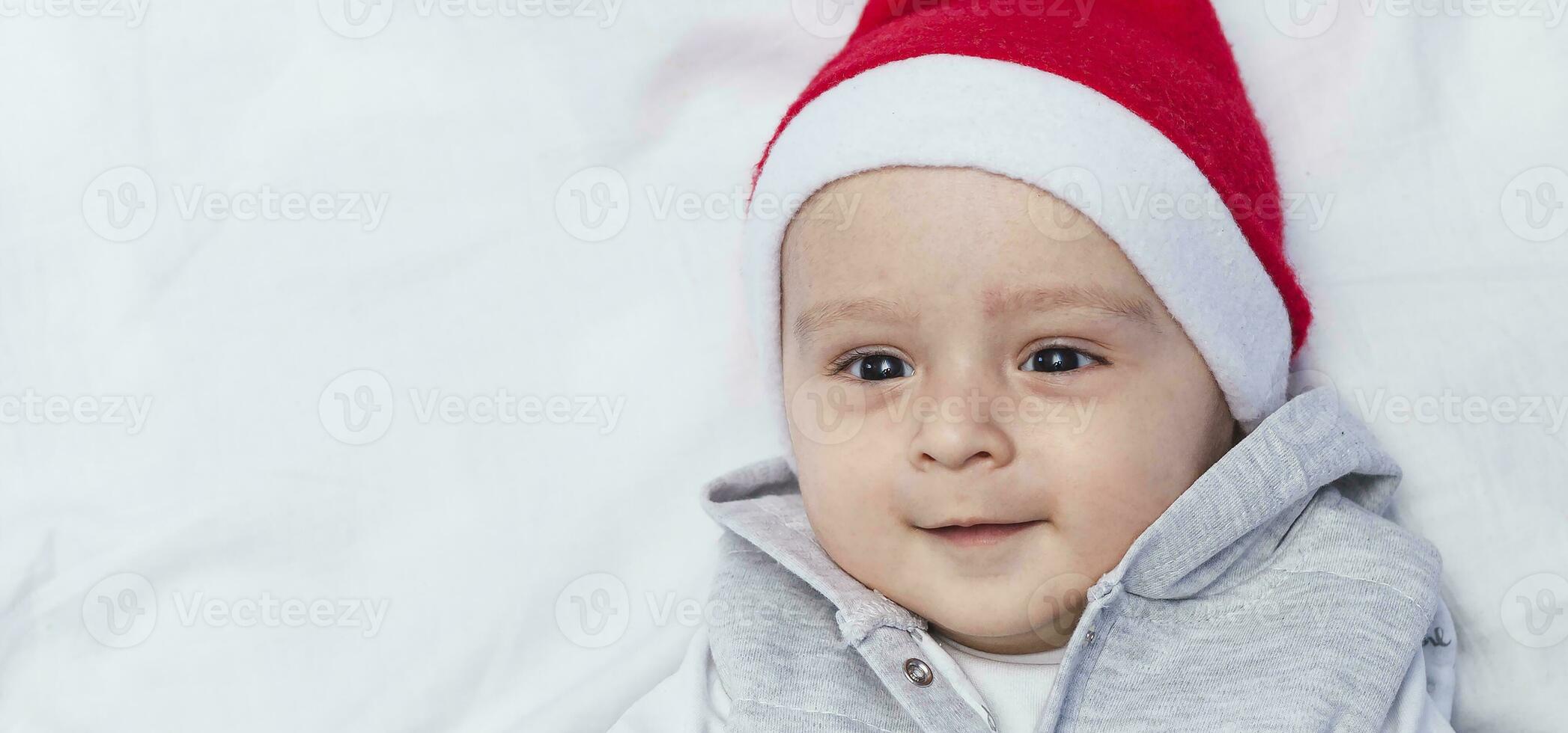 pequeño Papa Noel. 1 año antiguo bebé chico en Papa Noel claus gorra. Navidad niños foto