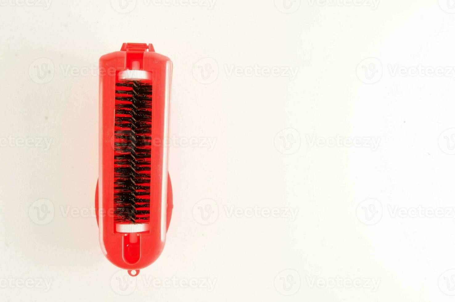 a red brush with a handle on a white surface photo