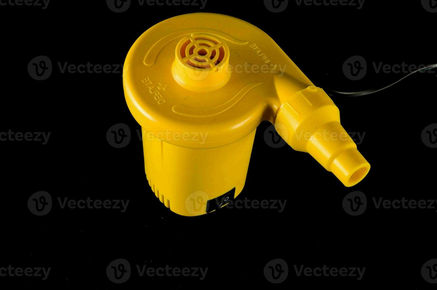 a yellow plastic pump on a black surface photo