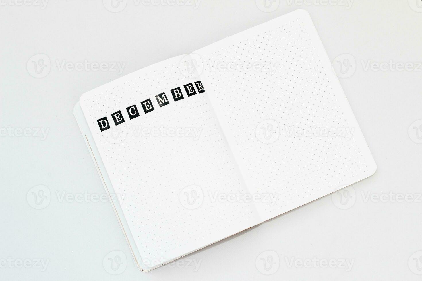 Filling in the diary, writing December in a notebook in a dot photo