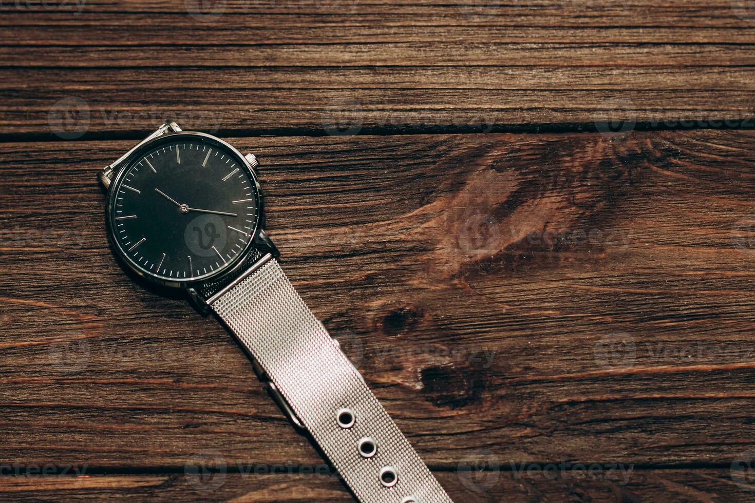 Wrist stylish watch with black dial on the table with brown planks. photo