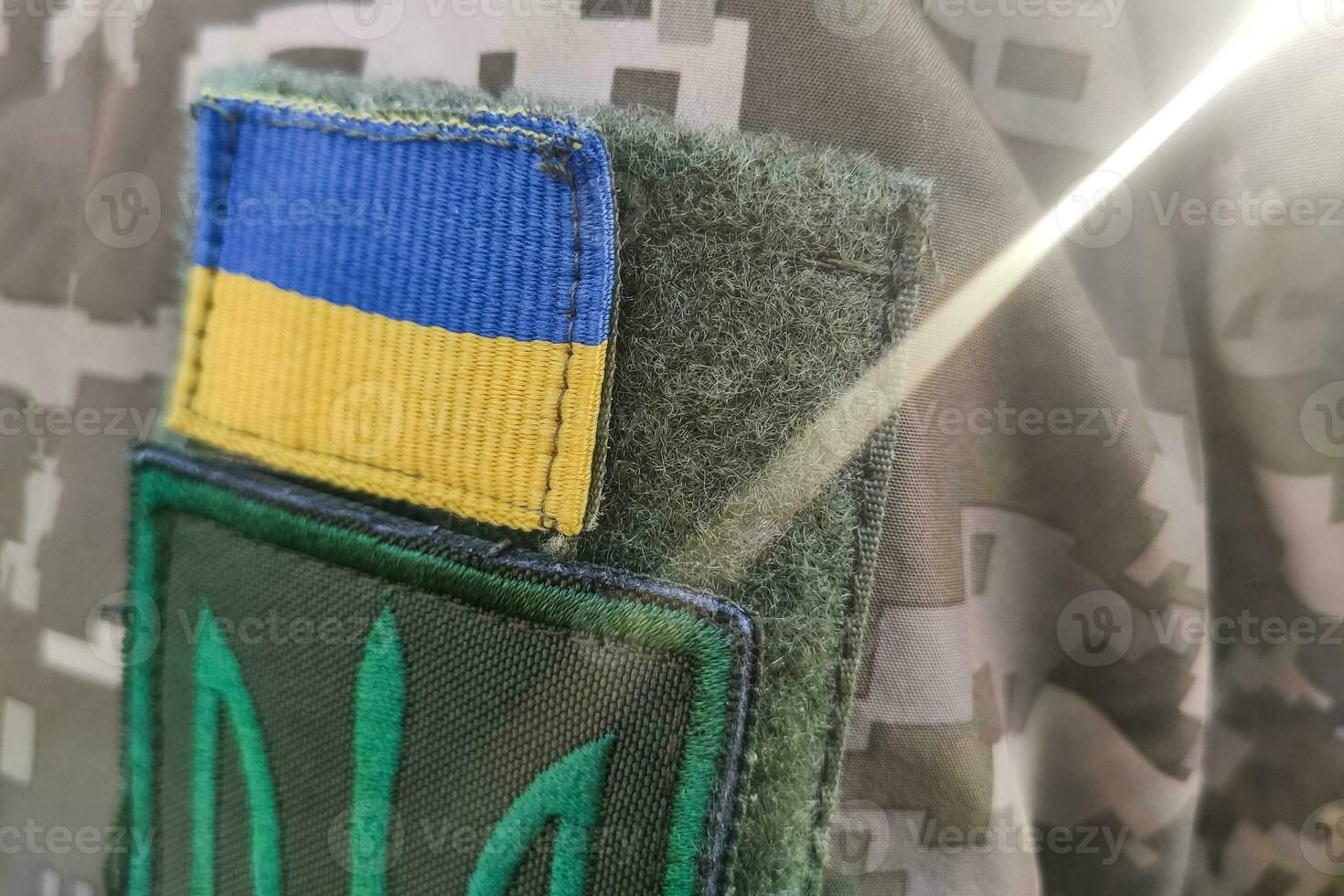Close-up texture pixel camouflage military uniform of the Armed Forces, chevron trident and flag of Ukraine photo