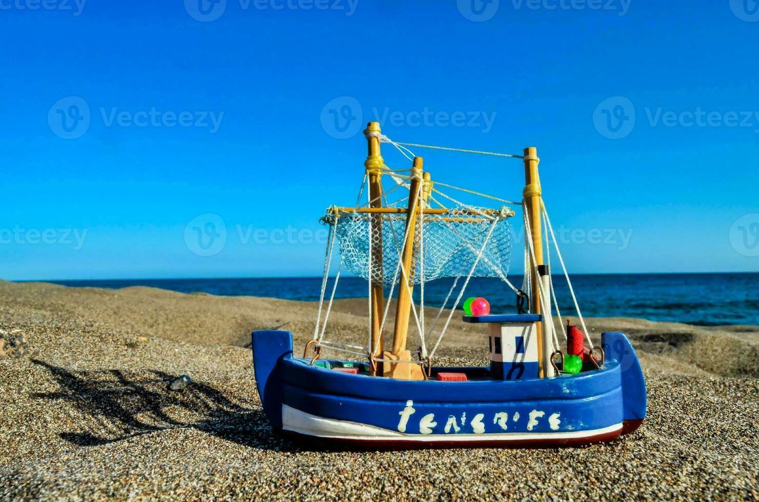 a toy boat on the beach with the ocean in the background photo