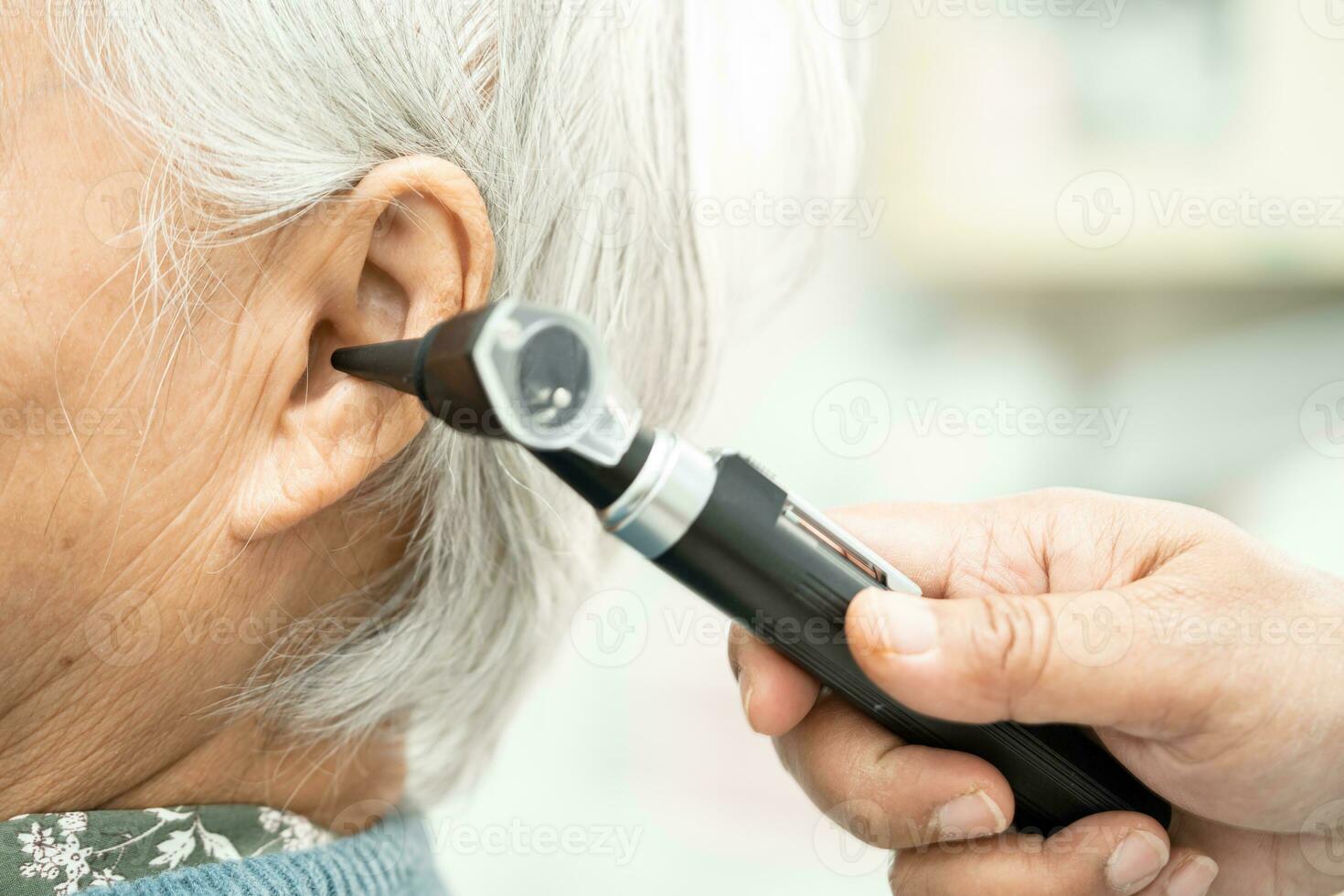 Audiologist or ENT doctor use otoscope checking ear of asian senior woman patient treating hearing loss problem. photo