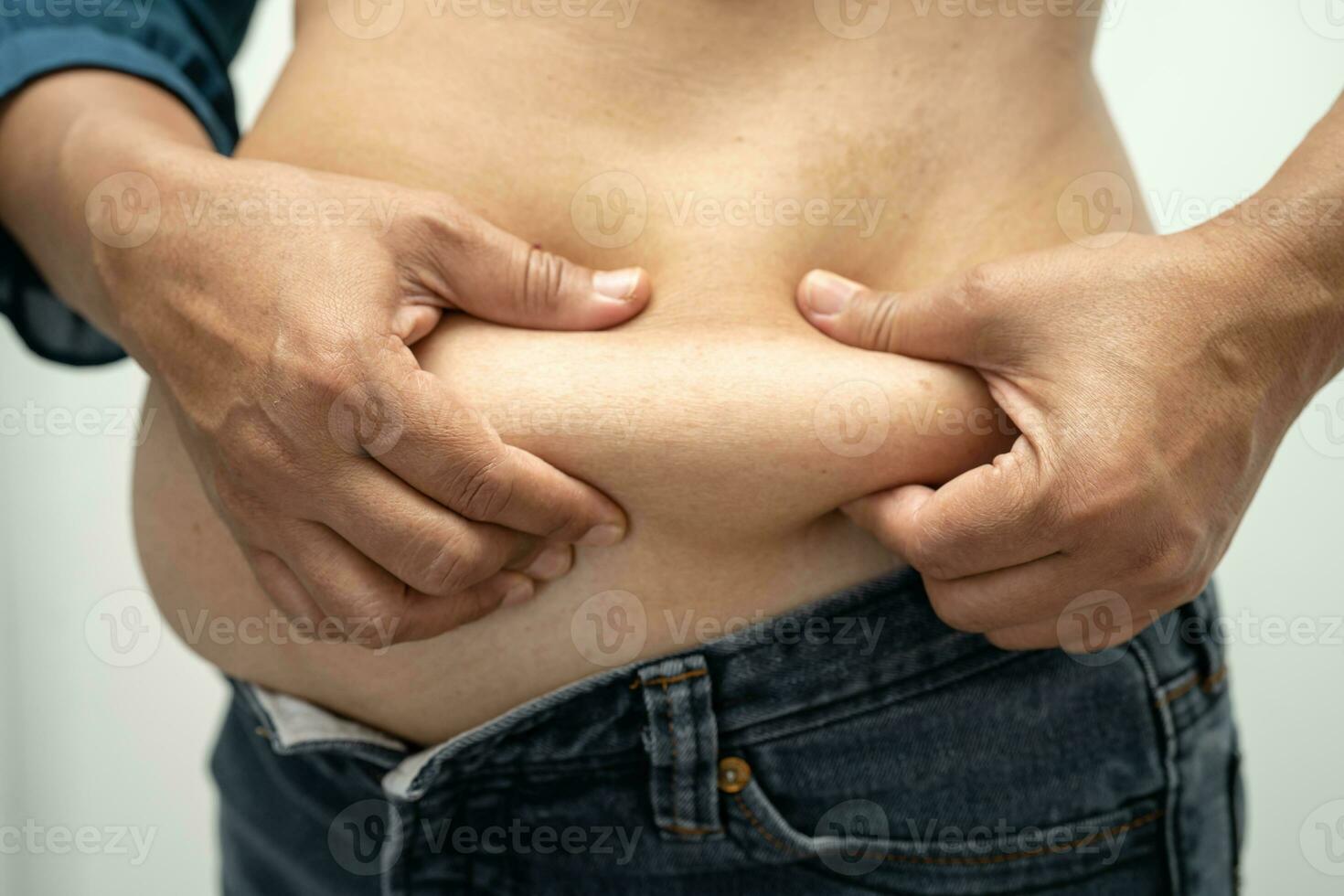 Overweight Asian woman show and use hand to squeeze fat belly. photo