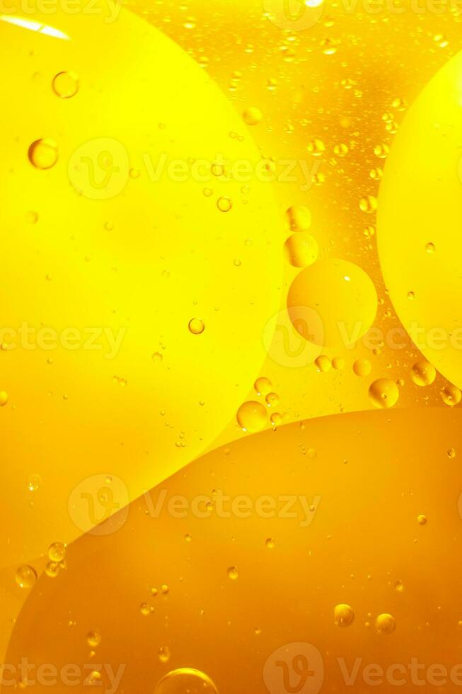 Gold Oil bubbles close up. circles of orange water macro. abstract shiny yellow background photo