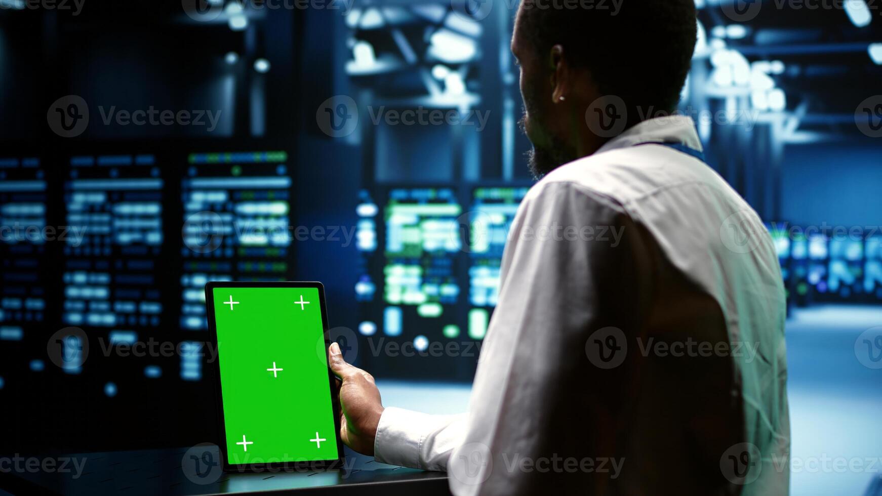 Technical support executive troubleshooting data center mainframes performance trends. Manager using chroma key tablet to spot high tech establishment operational issues causing hardware to slow down photo