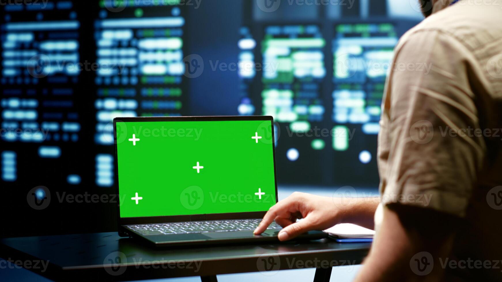 Computer scientist monitoring mainframes doing intense computations. Programmer using green screen laptop to assess strain on server room rigs caused by AI applications driving up power usage photo