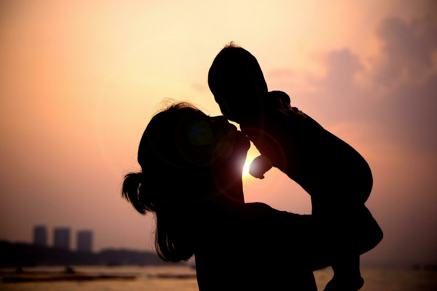 silueta de madre obras de teatro con su niñito en contra el puesta de sol. foto