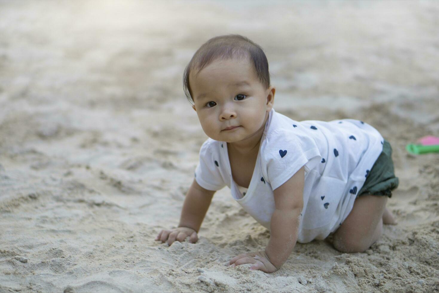 asiático niñito bebé tailandés niña jugando con arena foto