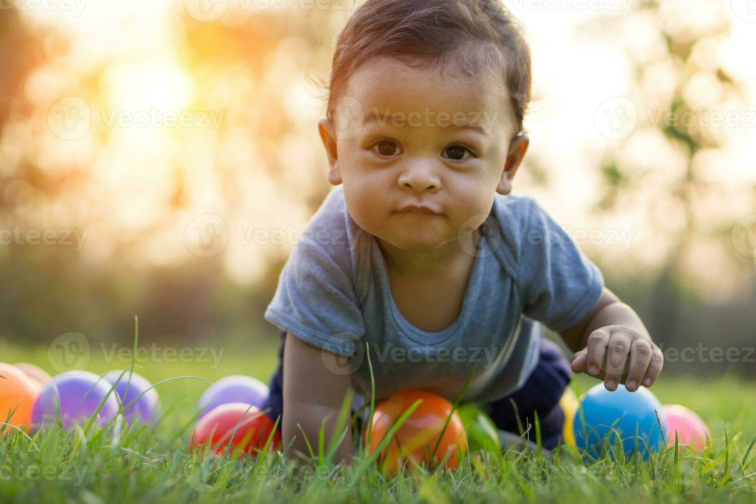 Cute asian baby crawling in the green grass and colorful ball photo