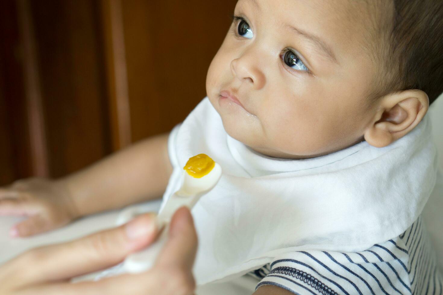 Eating from spoon of six month asian baby photo