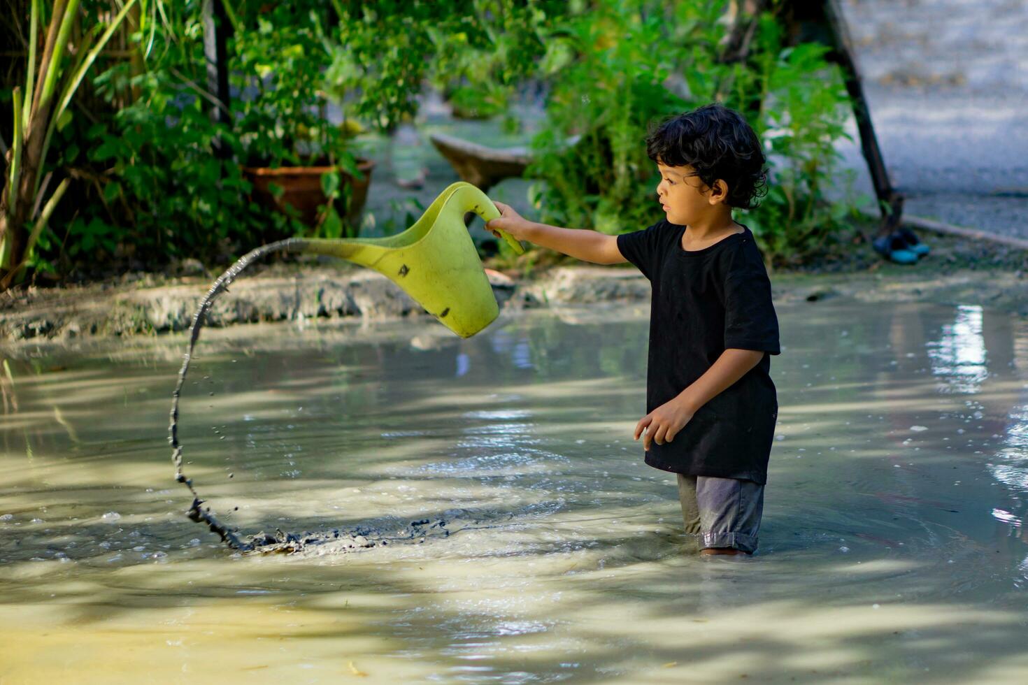 Asian boy playing with mud in a fun place inside a mud pit built for children to play together. photo