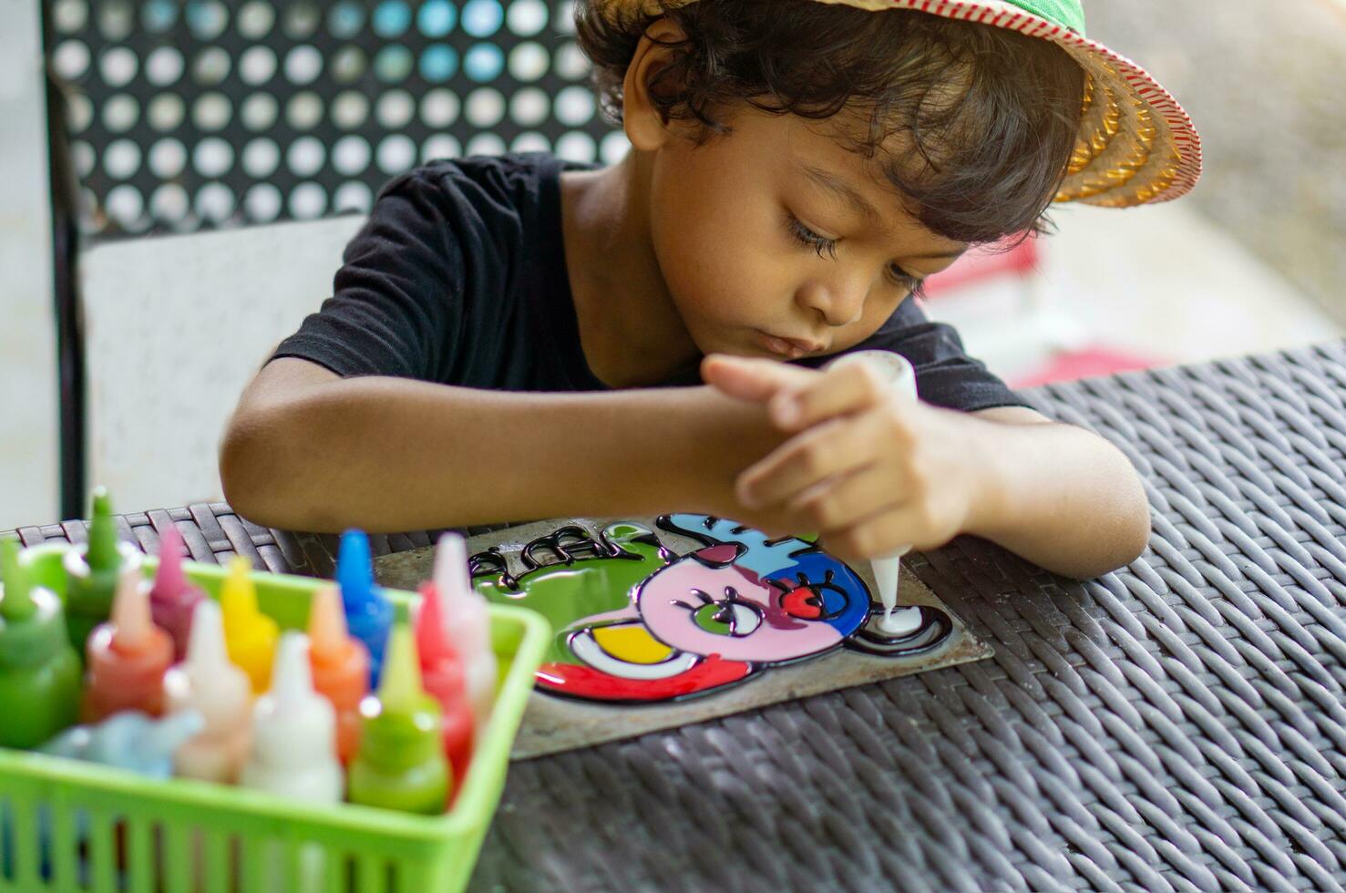 Asian boy is playing with plastic color paint on zinc sheet. photo