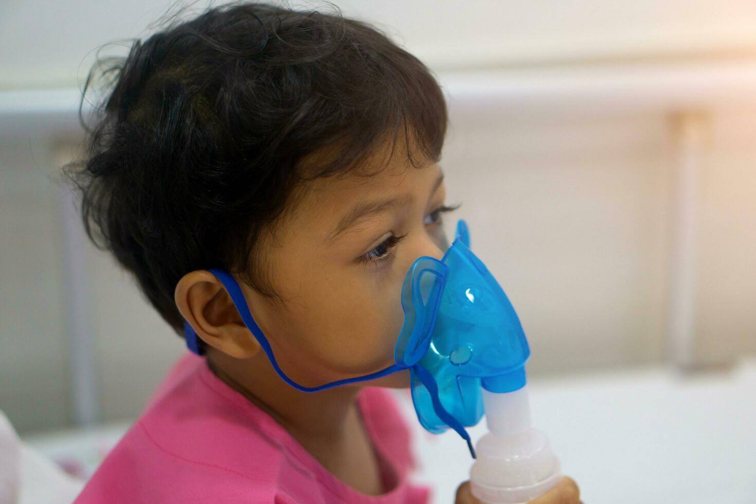 asiático niños chico 3 años antiguo tiene enfermo en nebulizador máscara foto