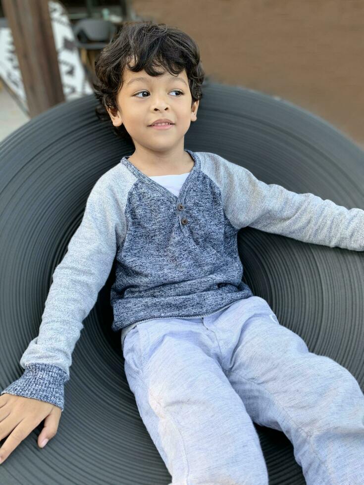 smiling Asian boy is sitting on a chair that can be swirled around by a force. photo