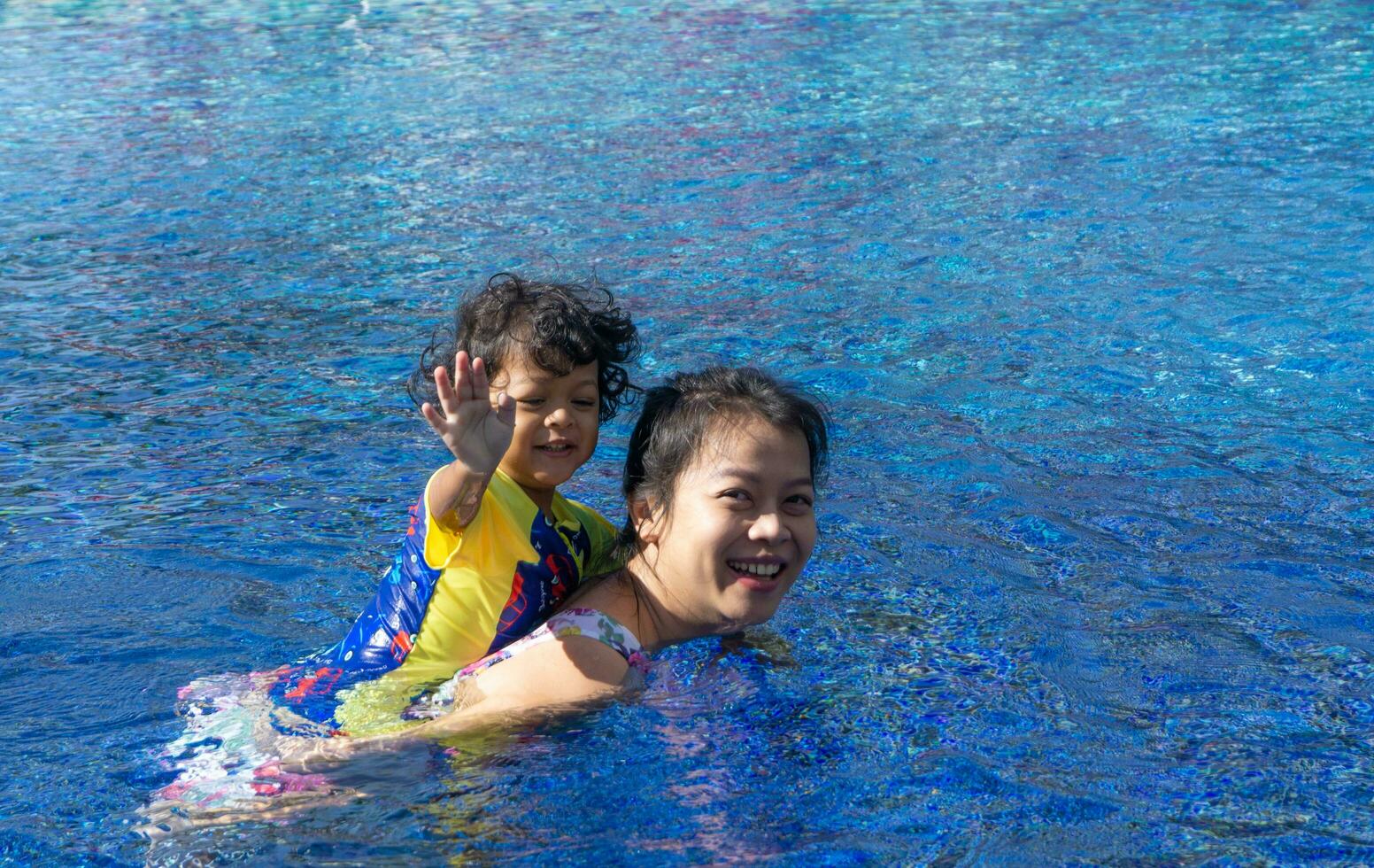 asiático niño chico aprender nadando en un nadando piscina con mamá. - puesta de sol filtrar efecto foto