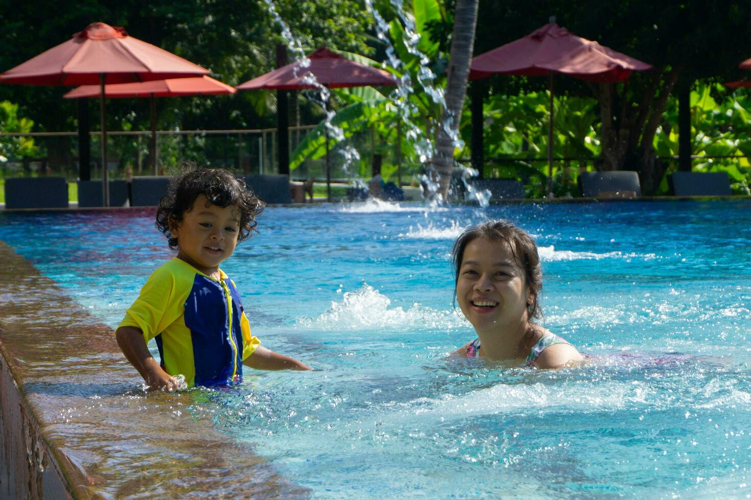 Asian child boy learn swimming in a swimming pool with mom photo
