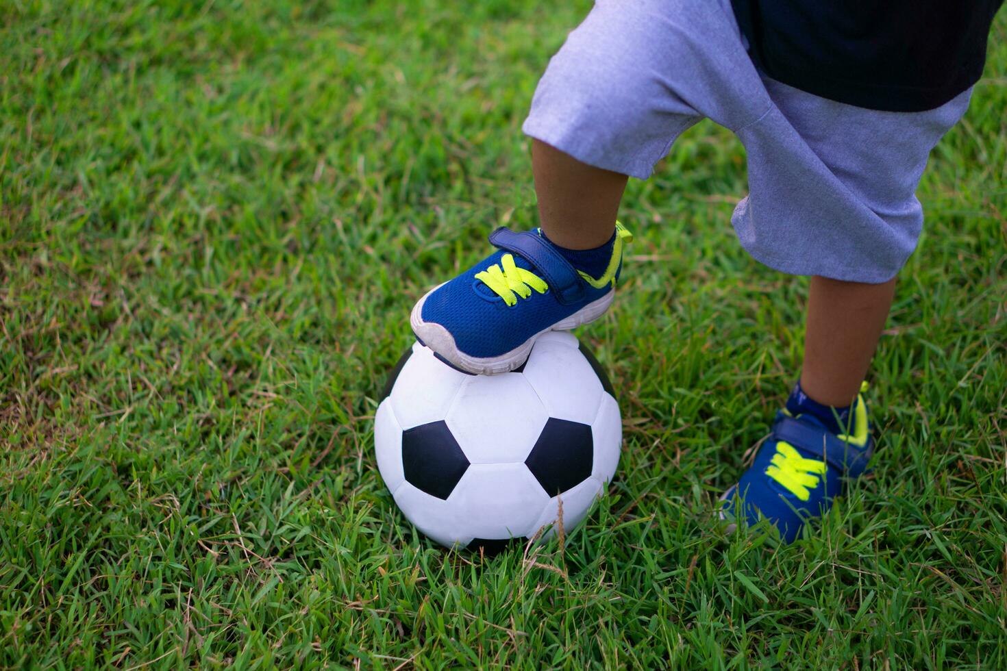 Asian kid playing soccer or football in the park. photo